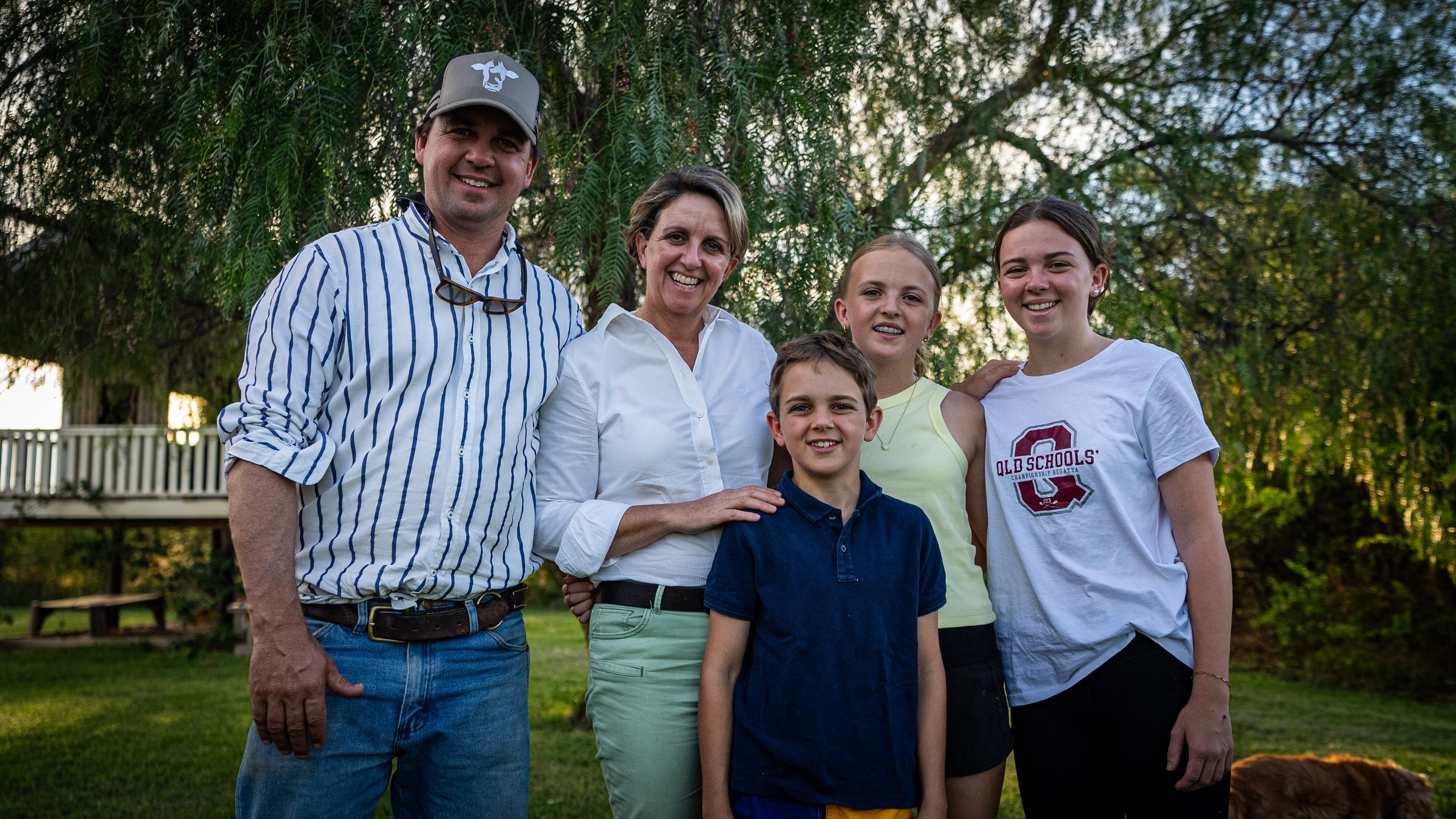 A mother and father stand with their three children under a three