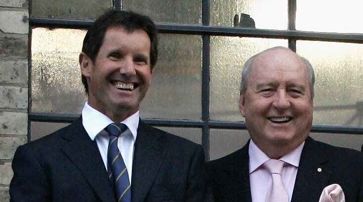 Alan Jones Robbie Deans, wearing suits, smile as they pose for a photo.