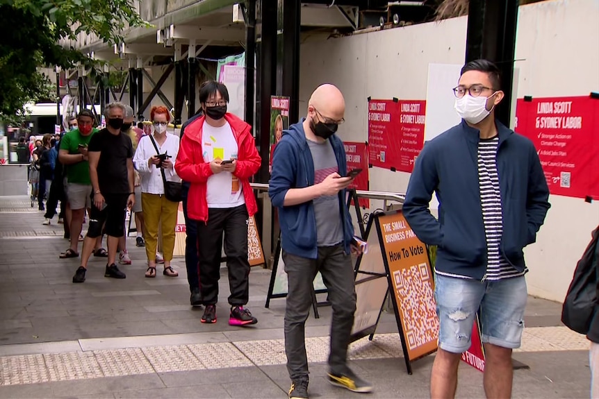 a group of voters line up outside a polling booth