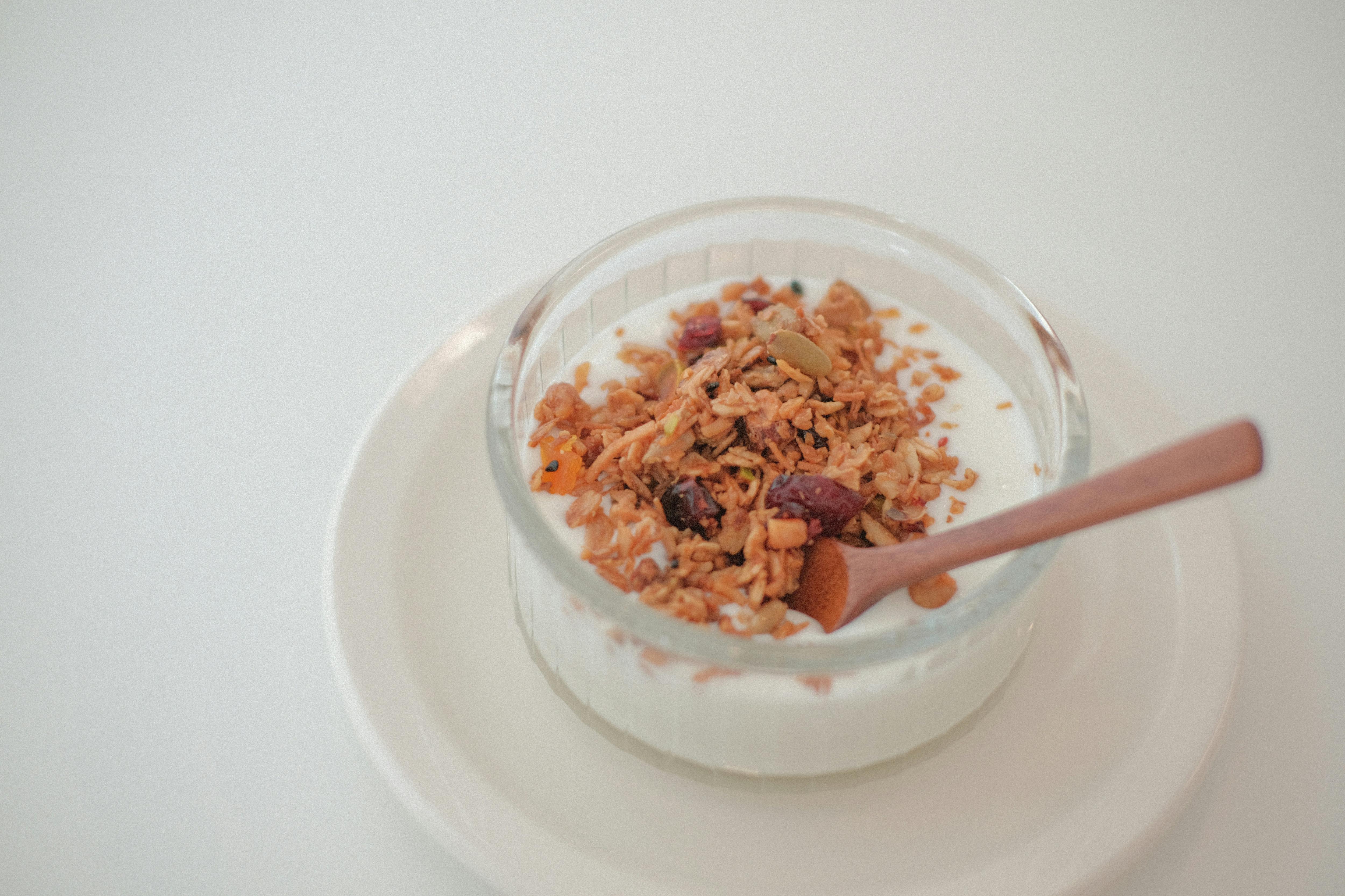 A picture of a yoghurt bowl with museuli and a wooden spoon.