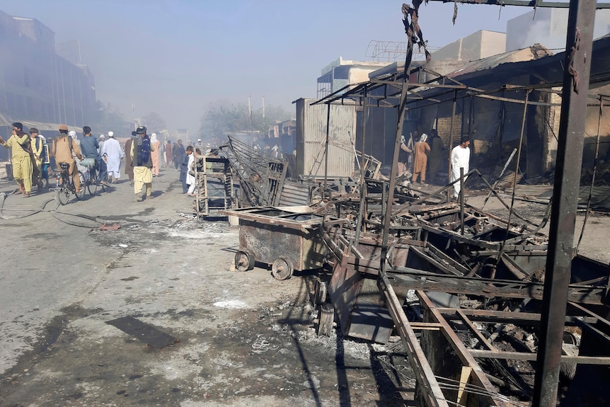 Afghans mill in the street, inspecting the damage to burnt out shops