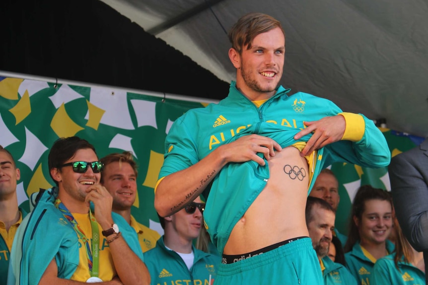 Kyle Chalmers lifts his shirt to show a tattoo on his ribs