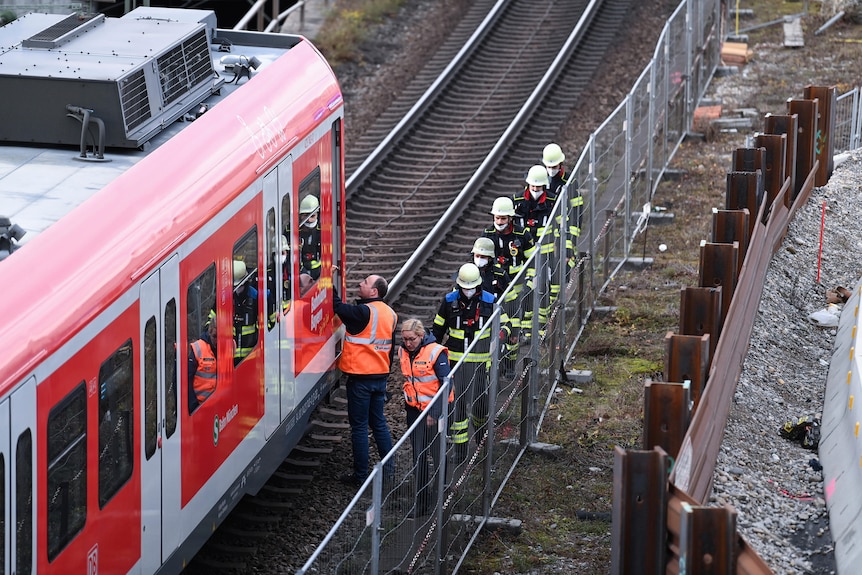 Firefighters go to a train together with railway staff