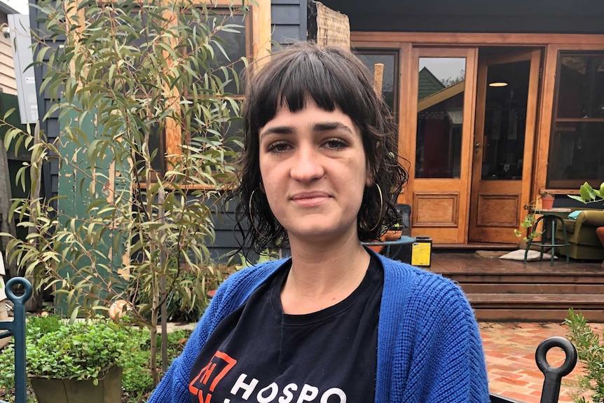 A young woman with a black shirt and blue cardigan.