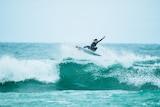 A surfer pulls off a trick on a wave during an event in Australia