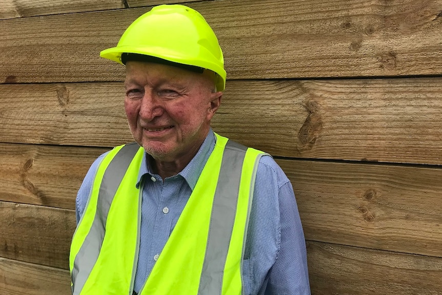 Peter Crowe, chairman of the Softwoods Working Group, wearing a fluoro helmet and best standing in a logging yard