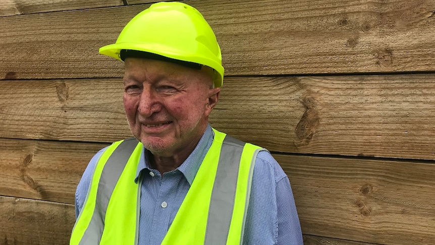 Peter Crowe, chairman of the Softwoods Working Group, wearing a fluoro helmet and best standing in a logging yard