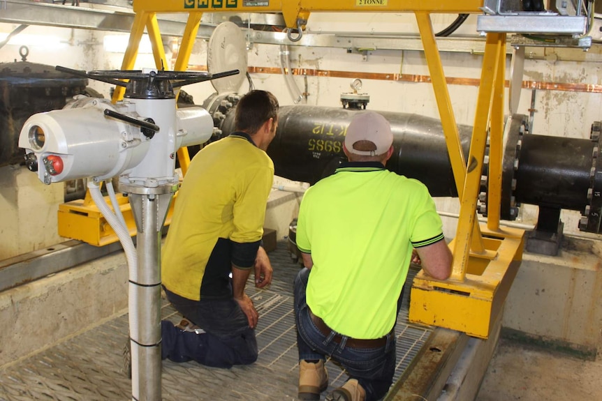Workers inspecting equipment in the underground pump chamber of the Captain Cook Memorial Jet.