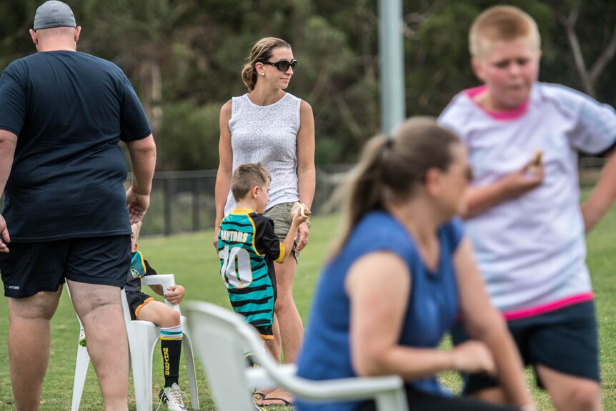 A mother stands with her son watching the Eastern Raptors training session in Boronia Victoria.