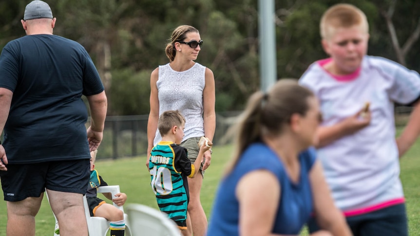 A mother stands with her son watching the Eastern Raptors training session in Boronia Victoria.