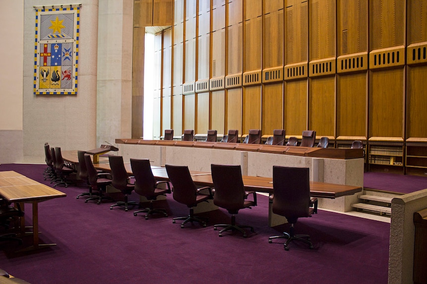 Seven high-backed judge's chairs in a row behind a bench on a raised platform faces the bar table inside the High Court