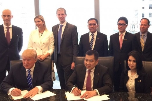 Donald Trump and Hary Tanoe sign papers surrounded by business associates, Ivanka Trump and Eric Trump.