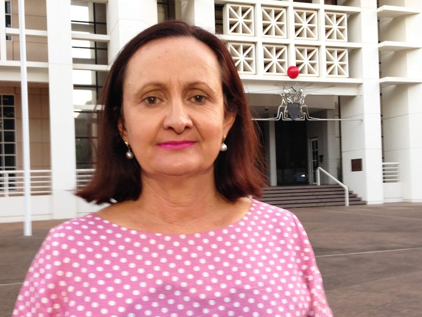 Robyn Lambley, standing outside a building, looks at the camera.