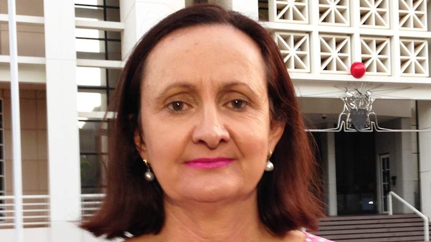 Robyn Lambley, standing outside a building, looks at the camera.