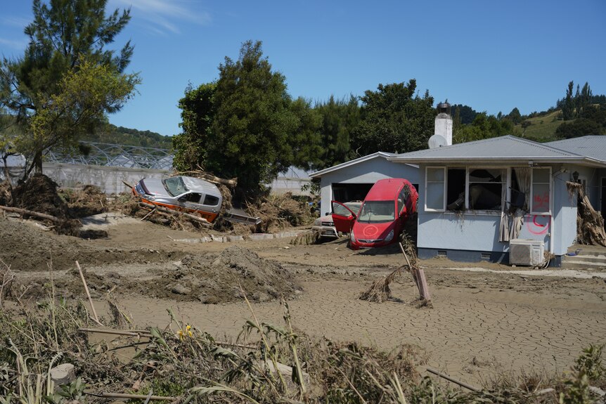 Two cars and a house damaged by a cyclone.