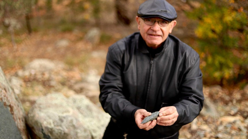 A man holds a sharp piece of stone in his hands.