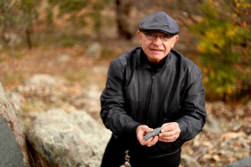 A man holds a sharp piece of stone in his hands.