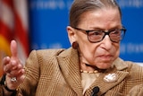 A seated Ruth Bader Ginsburg gestures with her right hand while speaking