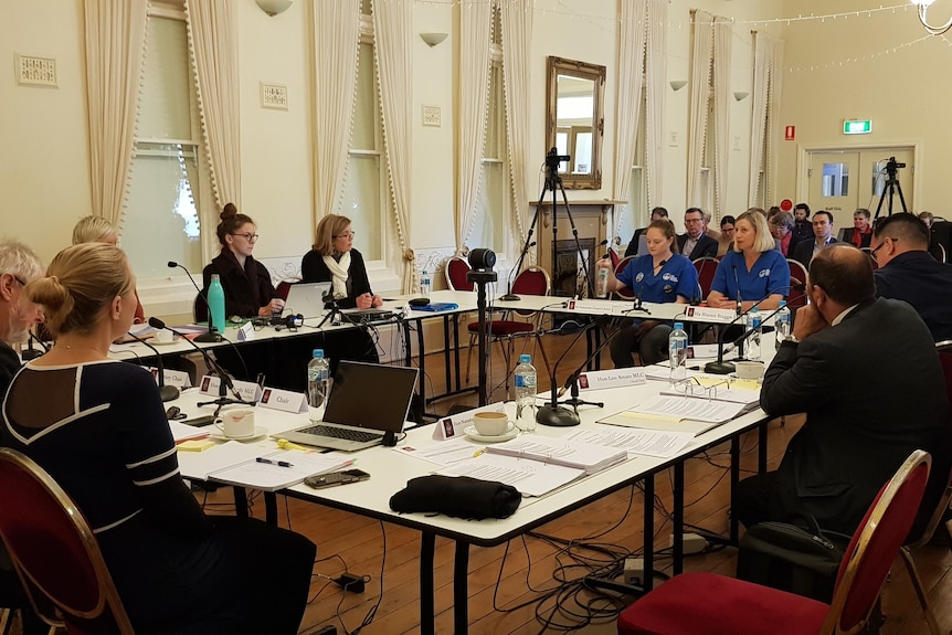 Two women in blue hospital scrubs sitting at a table.