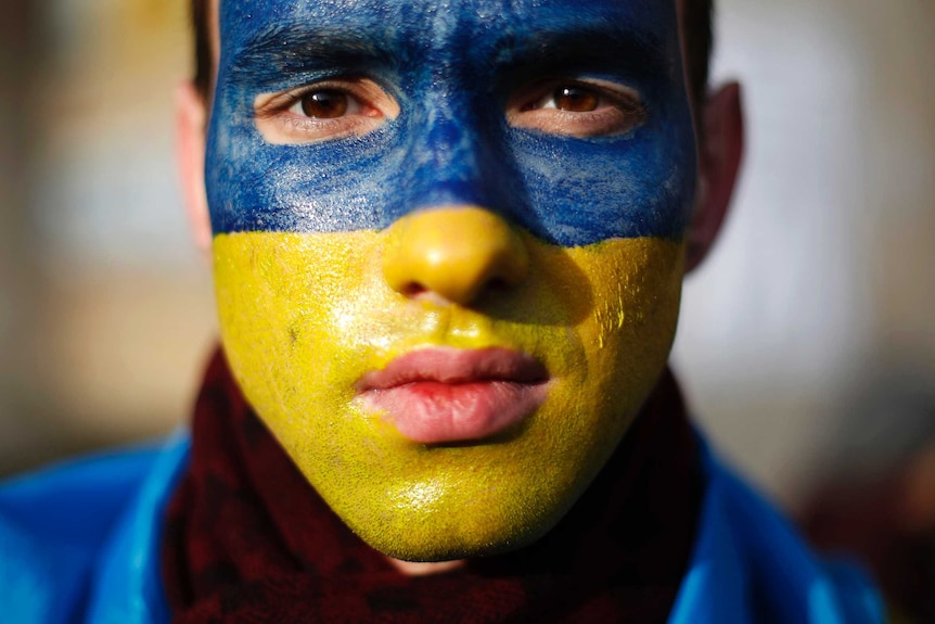 A man with his face painted in Ukrainian colours