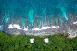 Drone shot of two houses on Christmas Island next to the ocean.