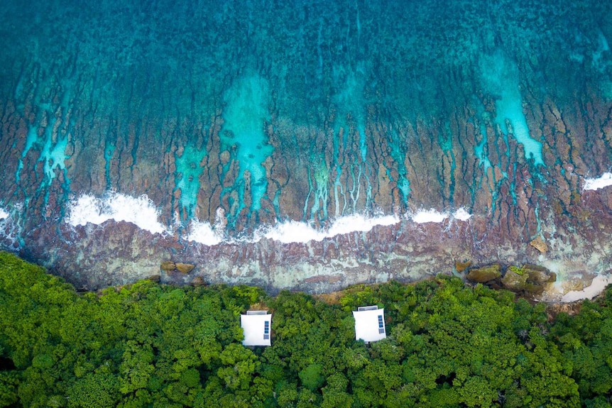 Drone shot of two houses on Christmas Island next to the ocean.