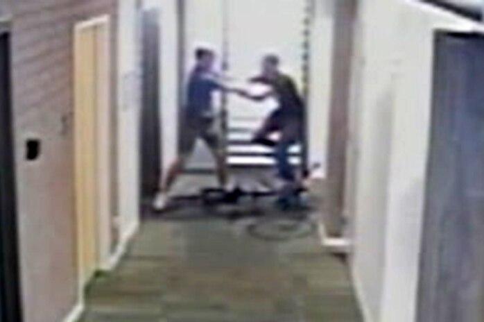 A grainy CCTV still of two men fighting in a corridor.
