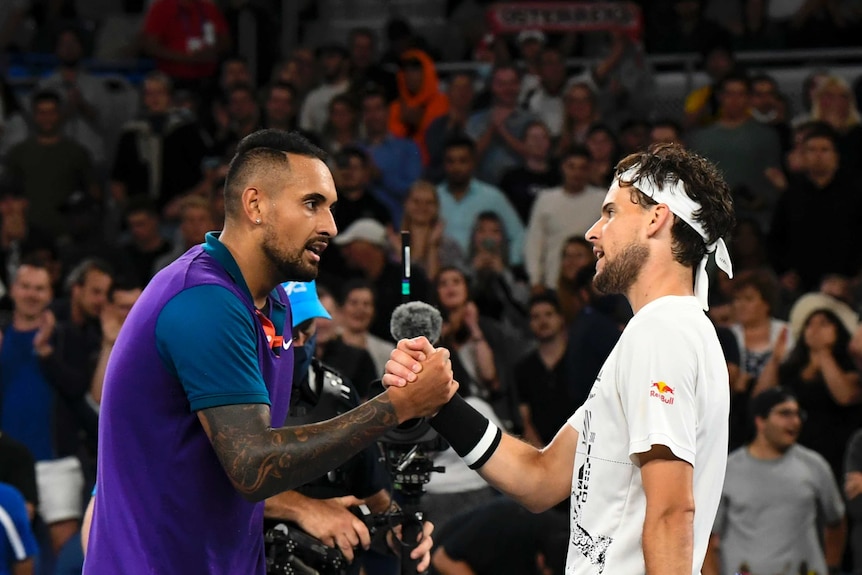 Nick Kyrgios and Dominic Thiem clasp hands over the net after their Australian Open tennis match.