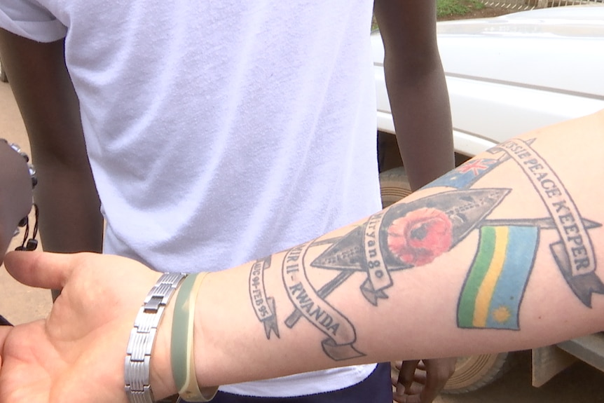 Miles Wootten shows some Rwandan locals his tattoo marking his time as a peacekeeper