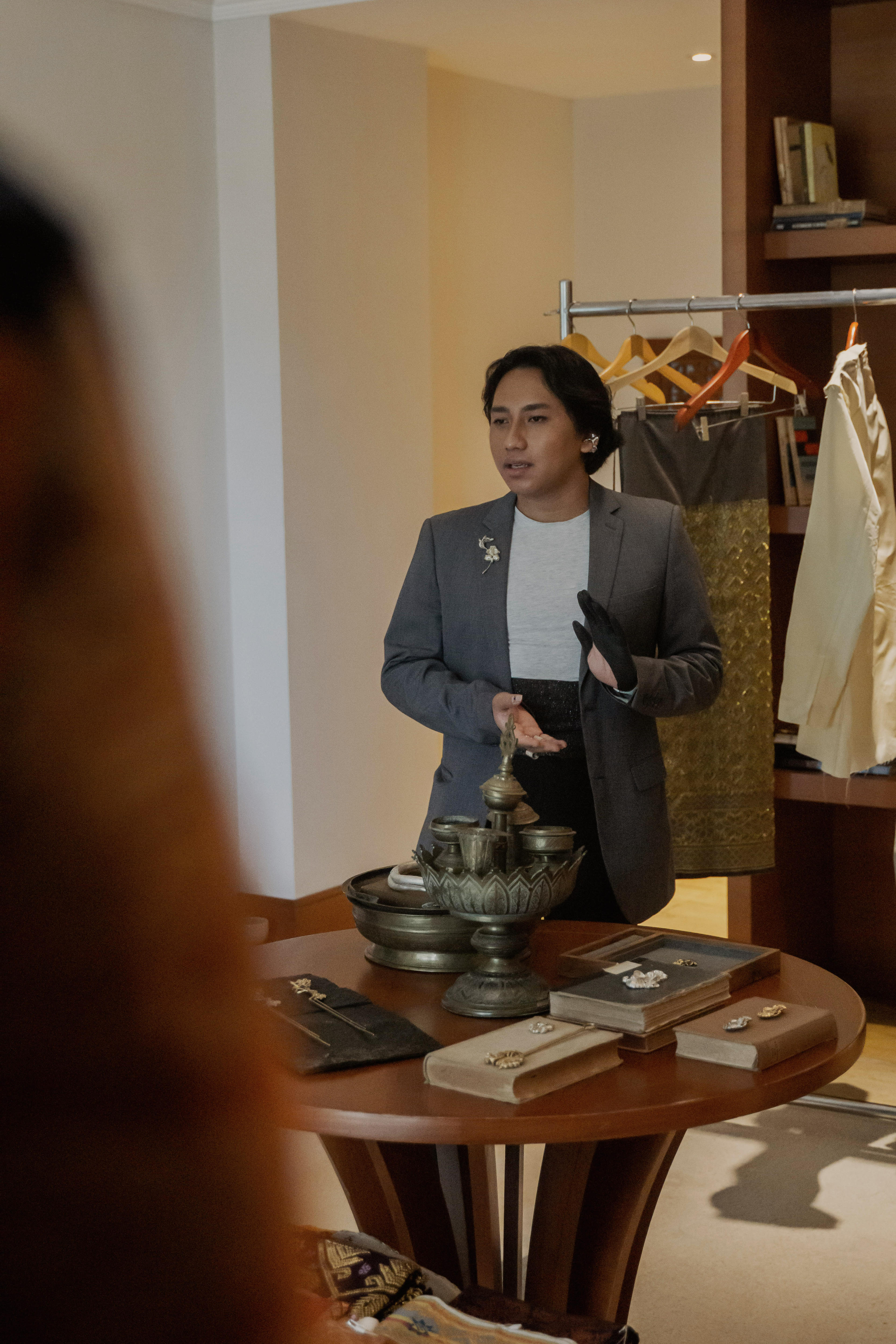Akib Aryou standing near some clothes on hangers.