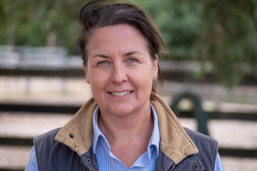 Woman with brown hair and blue eyes and blue shirt looking straight at camera