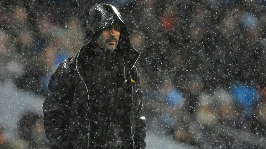 Pep Guardiola watches from the sideline in heavy rain as Manchester City plays Watford in the Premier League.