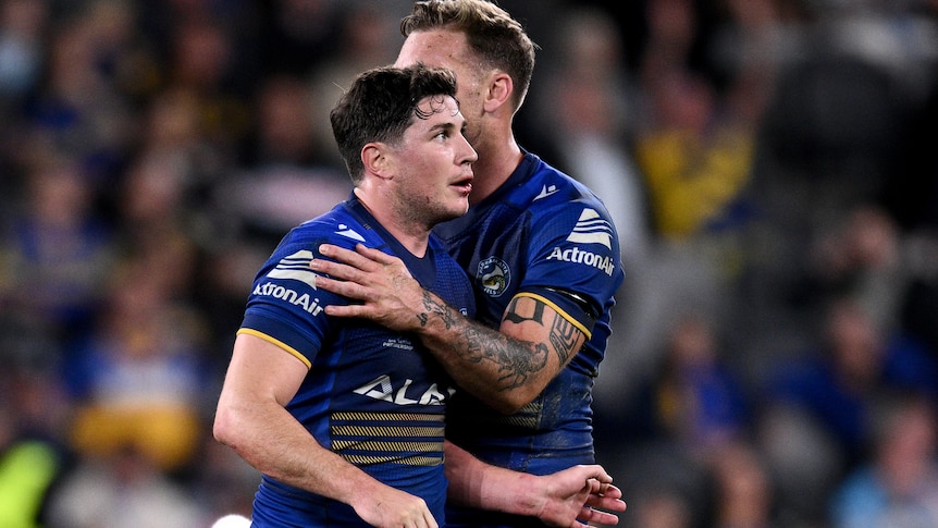 NRL player Mitchell Moses of the Eels is hugged by a teammate on the field