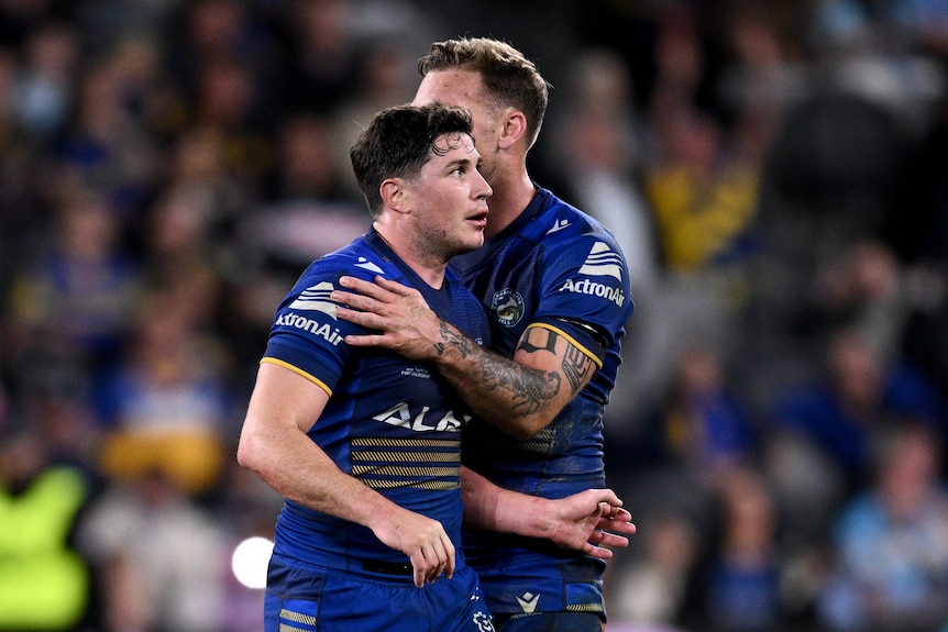 NRL player Mitchell Moses of the Eels is hugged by a teammate on the field