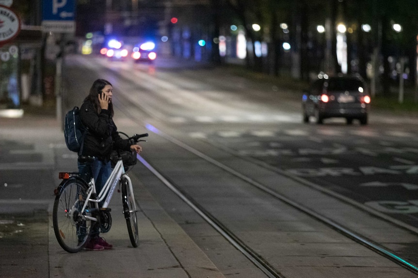 A woman making a phone call on her mobile while holding a bicycle.