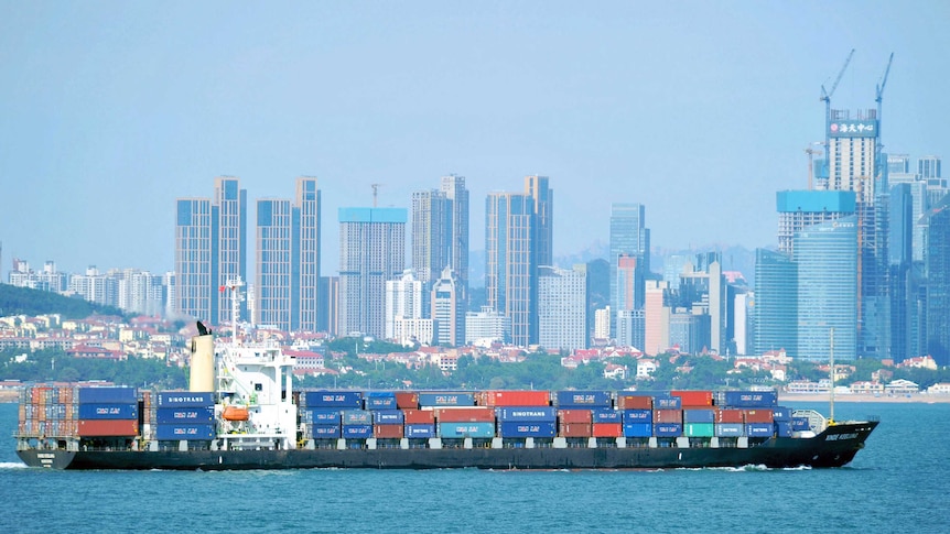 A container ship sails past the city skyline of Qingdao