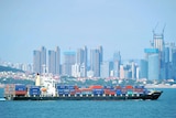 A container ship sails past the city skyline of Qingdao