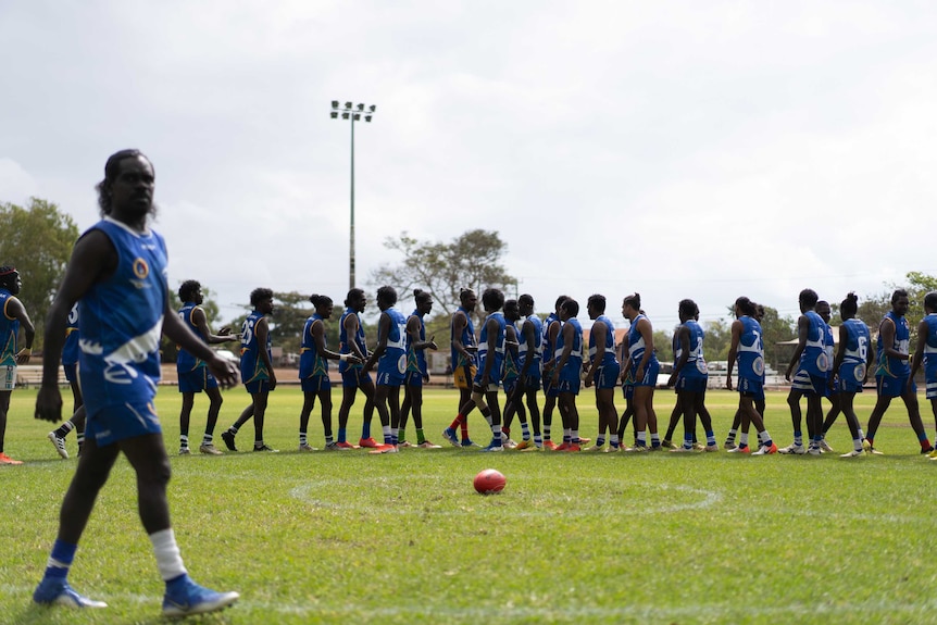 A ball sits in front of the players as the file past each other shaking hands.