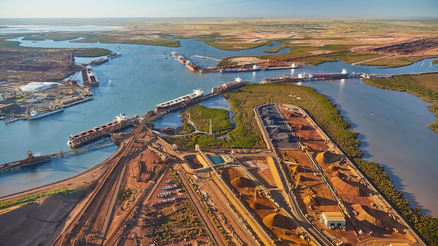 A port with vessels at berths and stacks of iron ore, as seen from above.