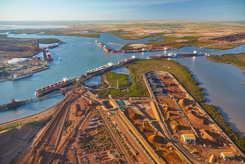 Aerial photo of a port with vessels at berths and stacks of iron ore