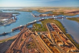 A port with vessels at berths and stacks of iron ore, as seen from above.