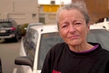 Wendy Morgan looks into the camera with tears in her eyes. She leans on the bonnet of a car.