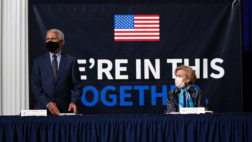 Senior US officials Dr Anthony Fauci and Dr Deborah Birx stand in front of a banner reading "we're in this together".