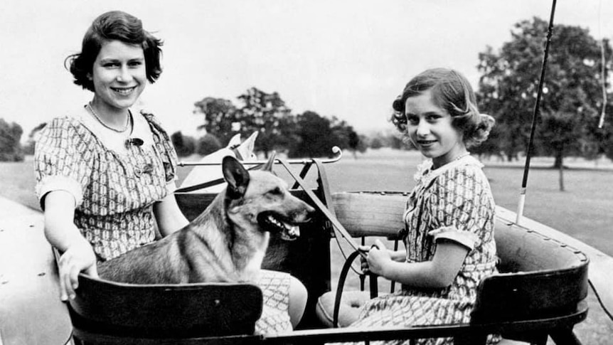 A black and white photo of Princess Margaret and the future Queen Elizabeth as children, sitting with a corgi