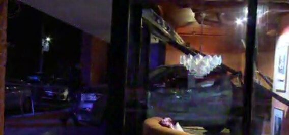 Por la noche, un todoterreno gris se encuentra entre cristales rotos en una tienda.