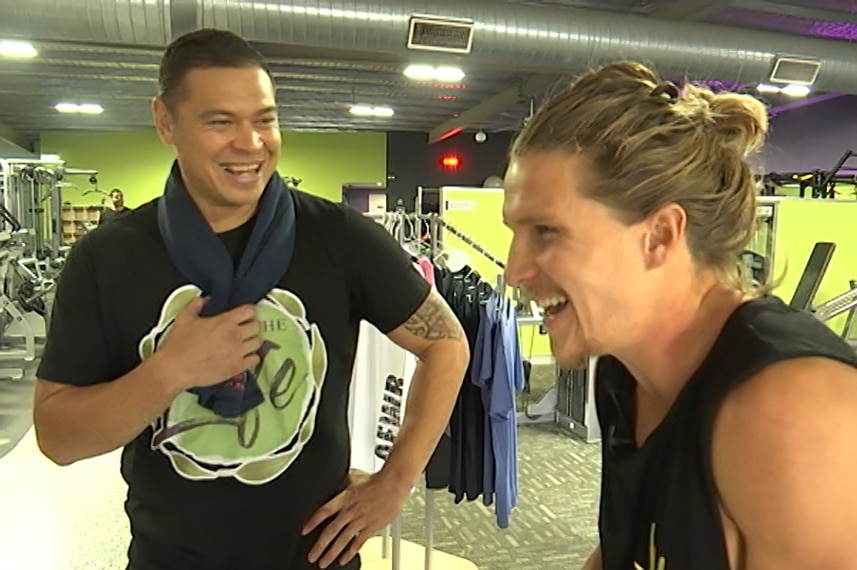 Two men enjoying a chat inside a gym.