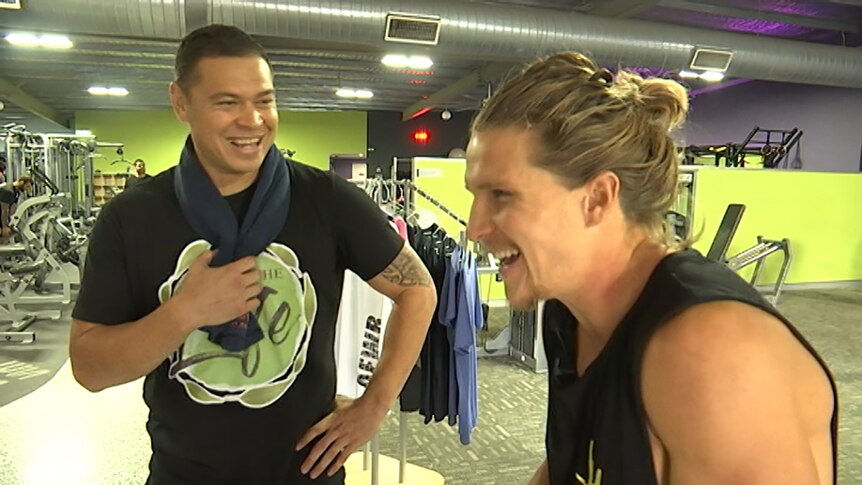 Two men enjoying a chat inside a gym.