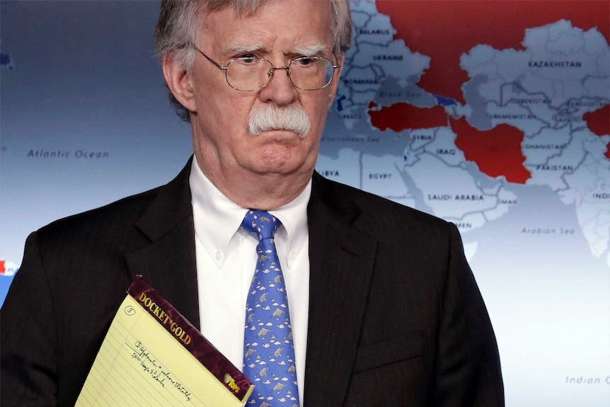 US national security adviser John Bolton grimaces while standing in front of a map.