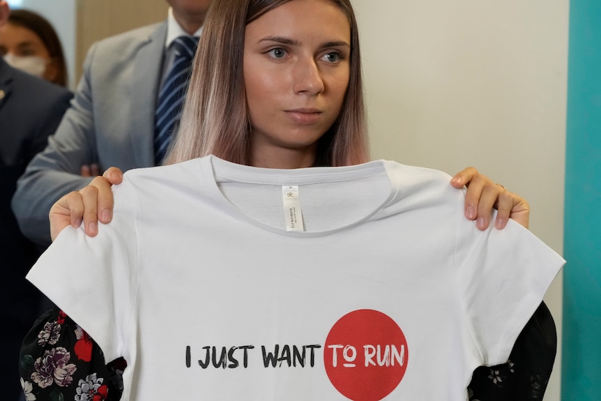 A woman holding a white shirt saying 'I just want to run'.