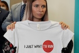 A woman holding a white shirt saying 'I just want to run'.